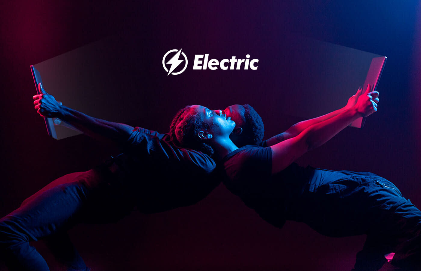 Two people, in dark clothing, lean back-to-back while holding tablets. The scene is lit with blue and pink spotlights. The word "Electric" with a lightning bolt icon is displayed prominently above them. The setting appears dynamic and futuristic, highlighting the IT company benefits of a Sparrow partnership.